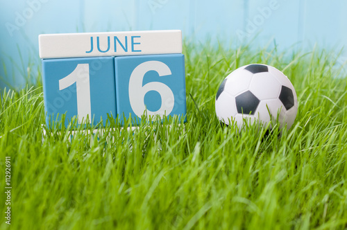 June 16th. Image of june 16 wooden color calendar on green grass background with football outfit. Summer day