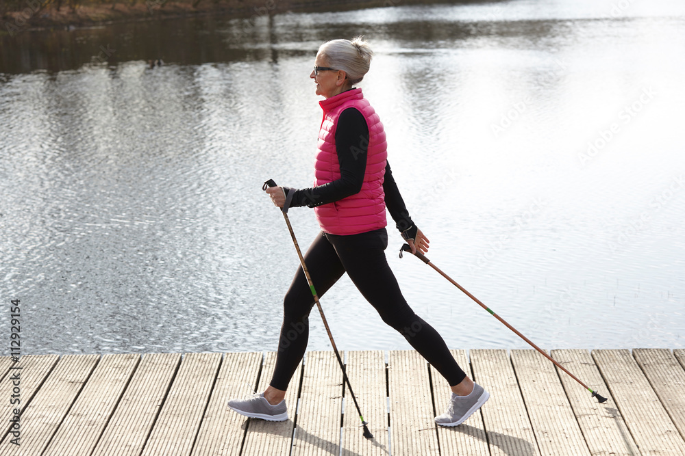 Full length side view of woman nordic walking by pond Stock Photo | Adobe  Stock
