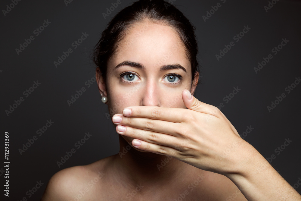 Beautiful young woman covering her mouth with hand. Isolated. Beautiful young woman covering her mouth with hand. Isolated.