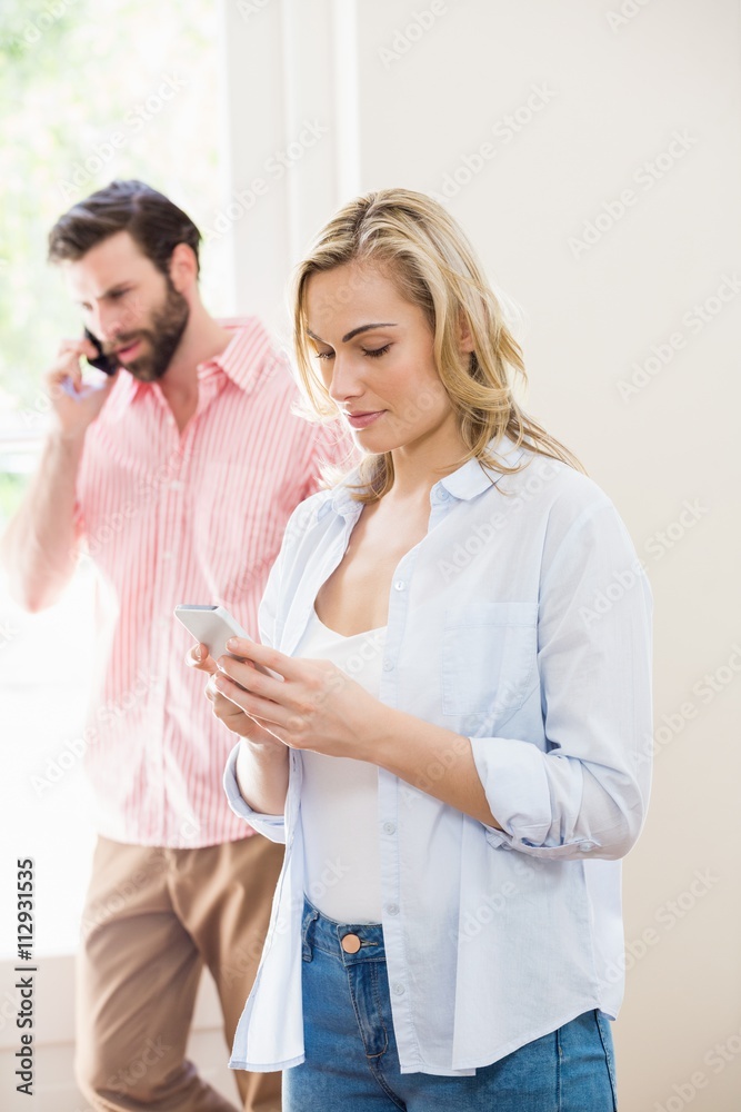 Woman texting messaging while man talking on mobile phone