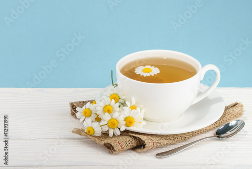 Cup of tea and chamomiles on wooden background
