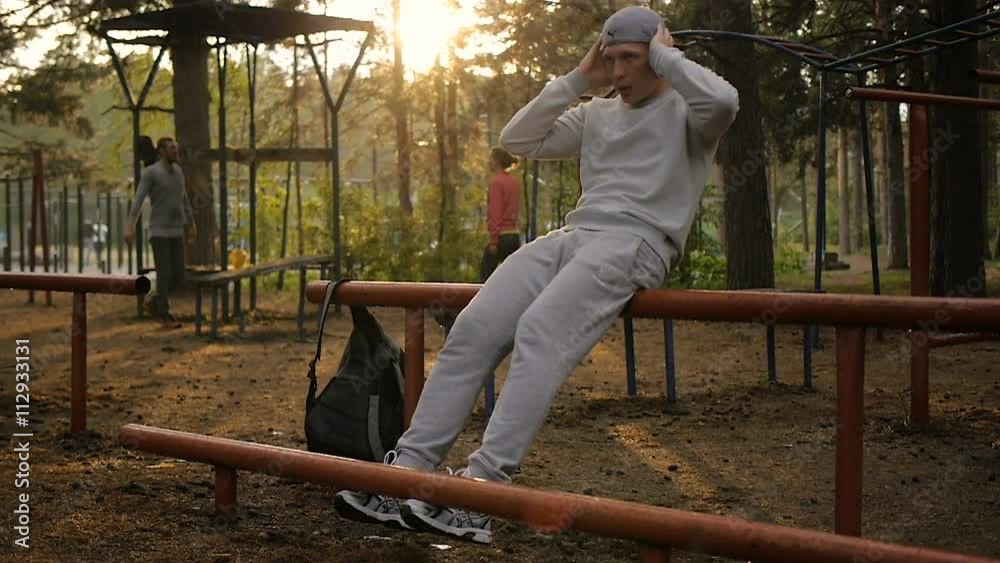 Young man doing exercise at the horizontal bar in the evening Young man doing exercise at the horizontal bar in the evening