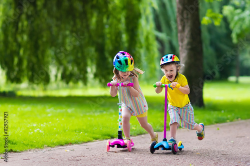 Little kids riding colorful scooters