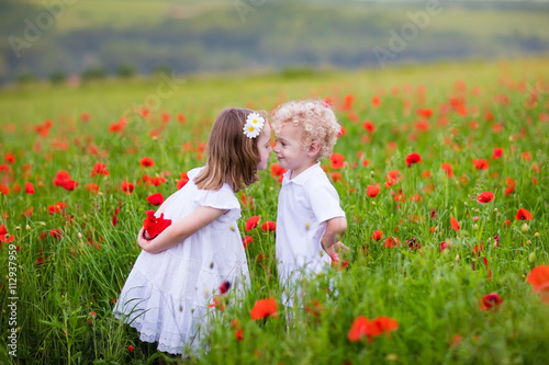 Kids playing in red poppy flower field