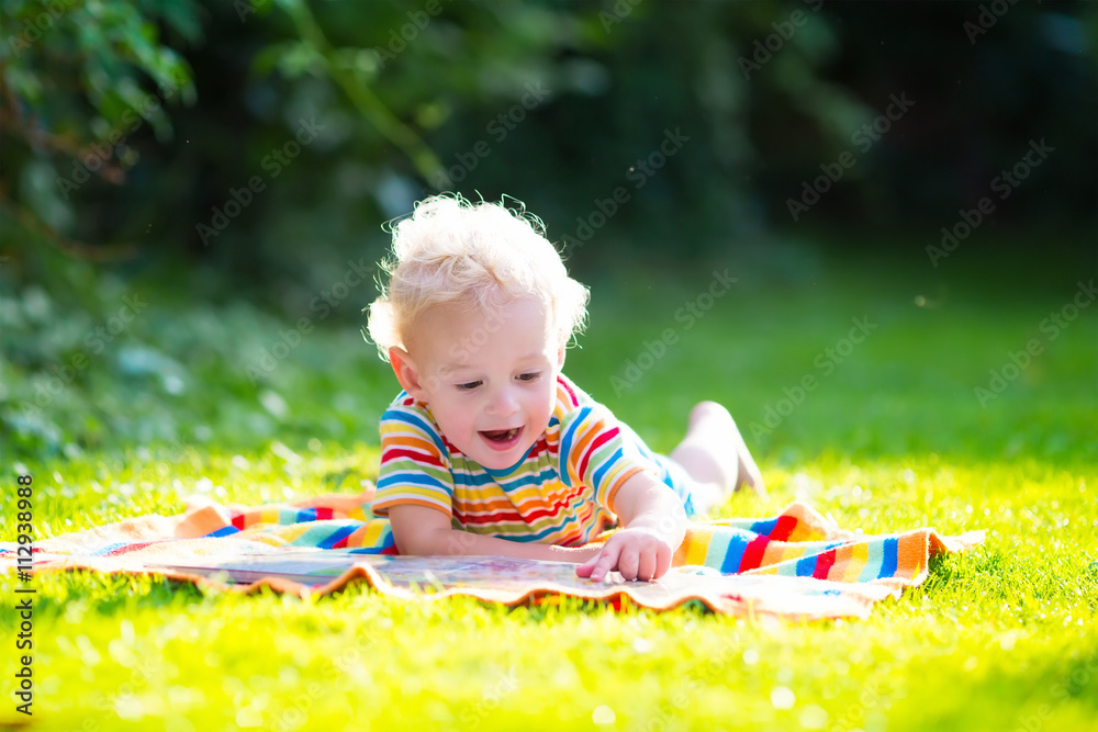 Little boy reading in summer garden Little boy reading in summer garden