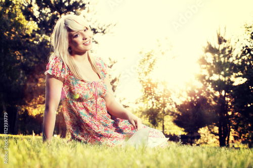 Blonde young woman girl relaxing in a park reading book, sitting alone on grass photo
