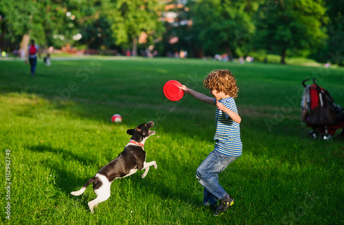 The boy plays on a lawn with dog.