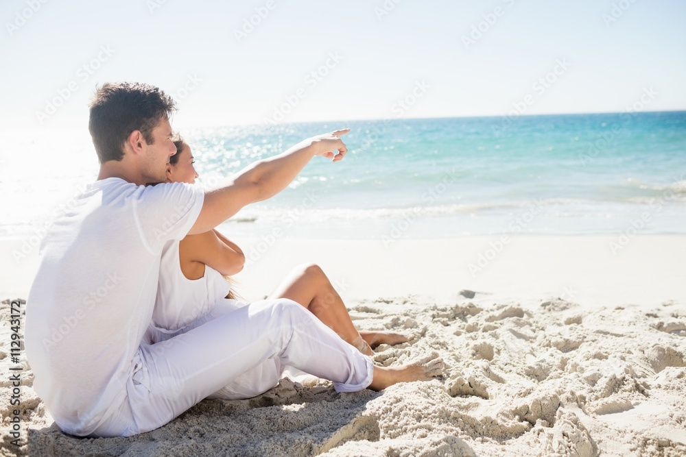 Cute couple sitting down on the beach