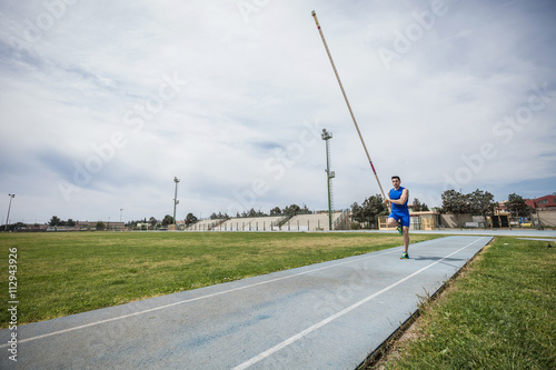 Young male pole vaulter sprinting with pole vault at sport facility