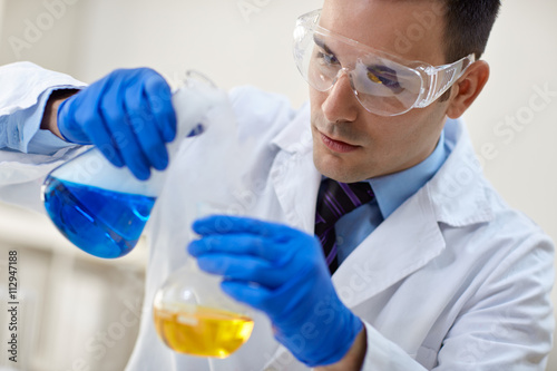 close up of young male scientist with flask making test or resea