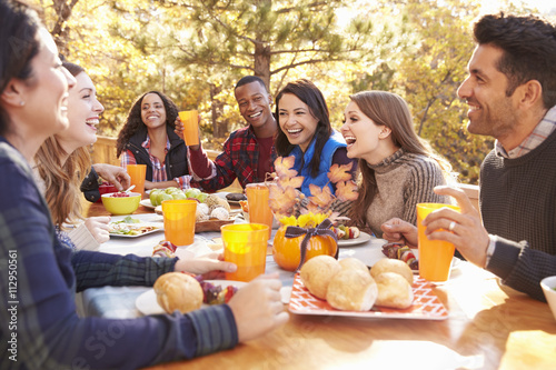 Group of happy friends eat and laugh at a table at a barbecue