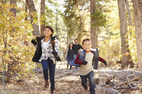 Parents watching their children running in a forest © Monkey Business