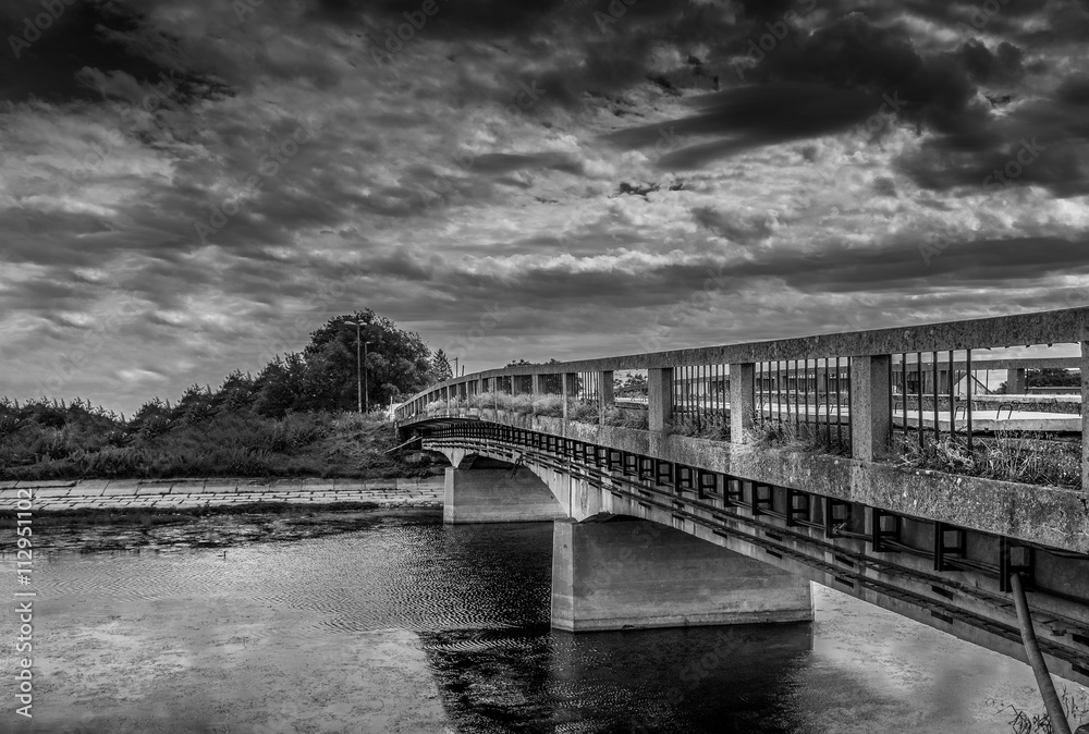 Panorama of old abandoned bridge across river in black and white