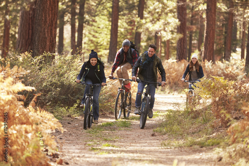 Group of friends riding bikes on a forest path, front view