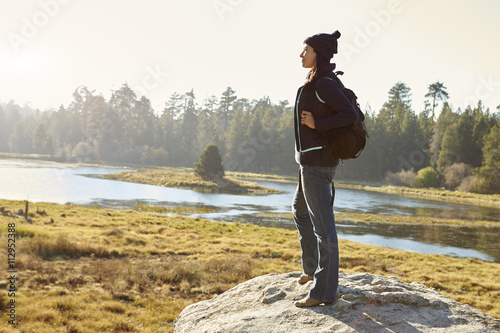 Young adult woman standing alone on a rock in countryside Fototapet