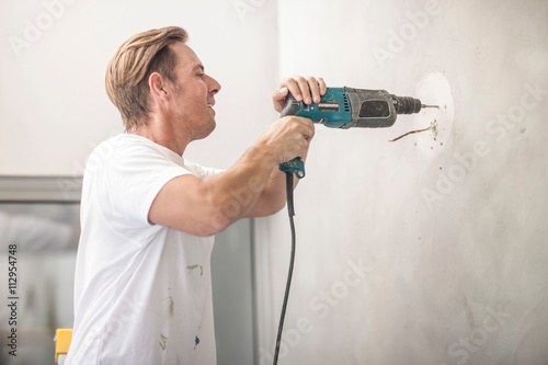 Builder drilling into wall