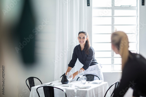 Waitresses chatting and setting table in restaurant