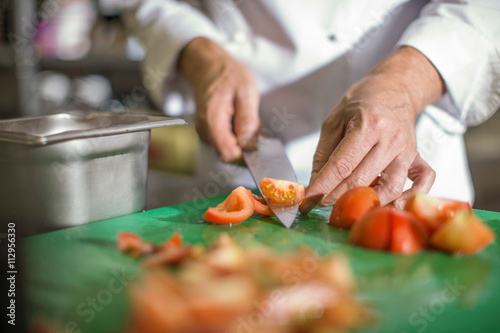 Chef slicing tomatoes on table