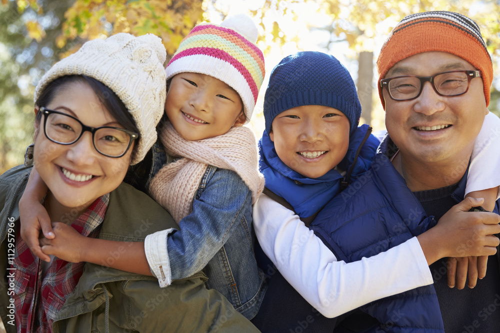 Portrait of an Asian family with two kids piggybacking parents Portrait of an Asian family with two kids piggybacking parents