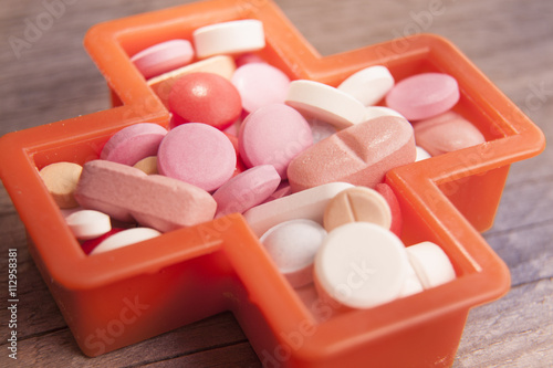 Various medicinal pills  in a cross shape on a wooden background