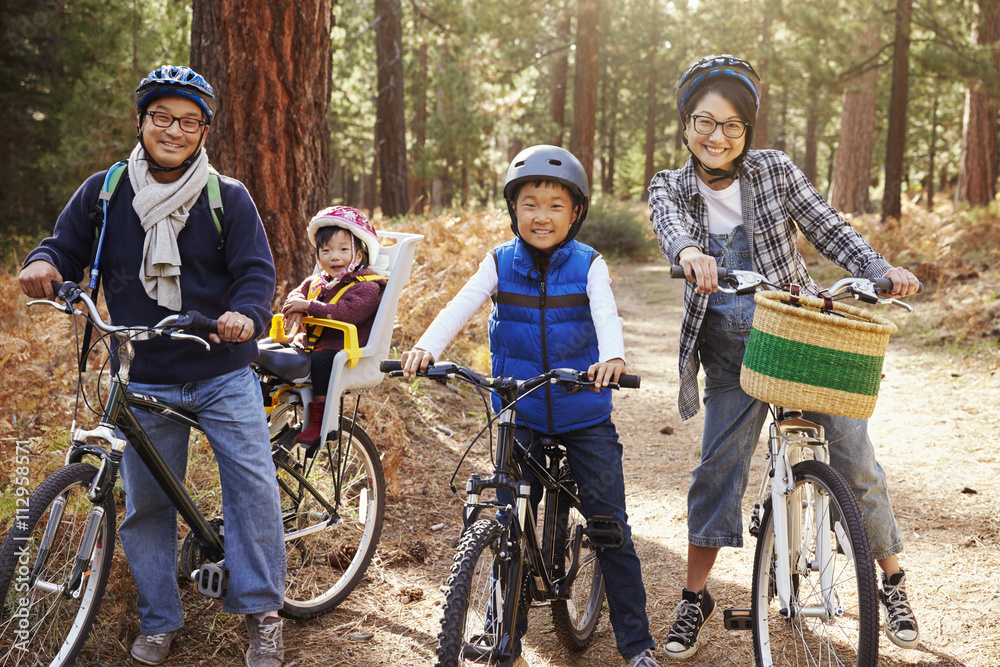 Portrait of an Asian family on bikes in a forest, close up