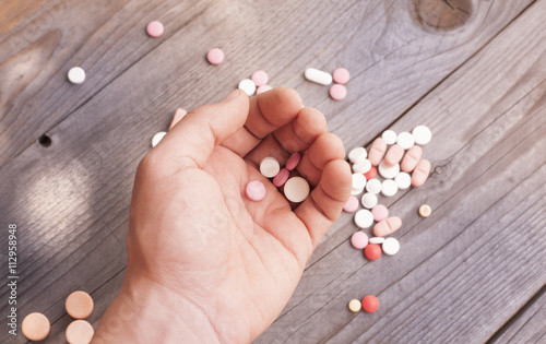 Macro photograph of various colorful medicinal pills - holding pills in the hand