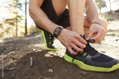 Man ties sports shoe before run in a forest, close up detail