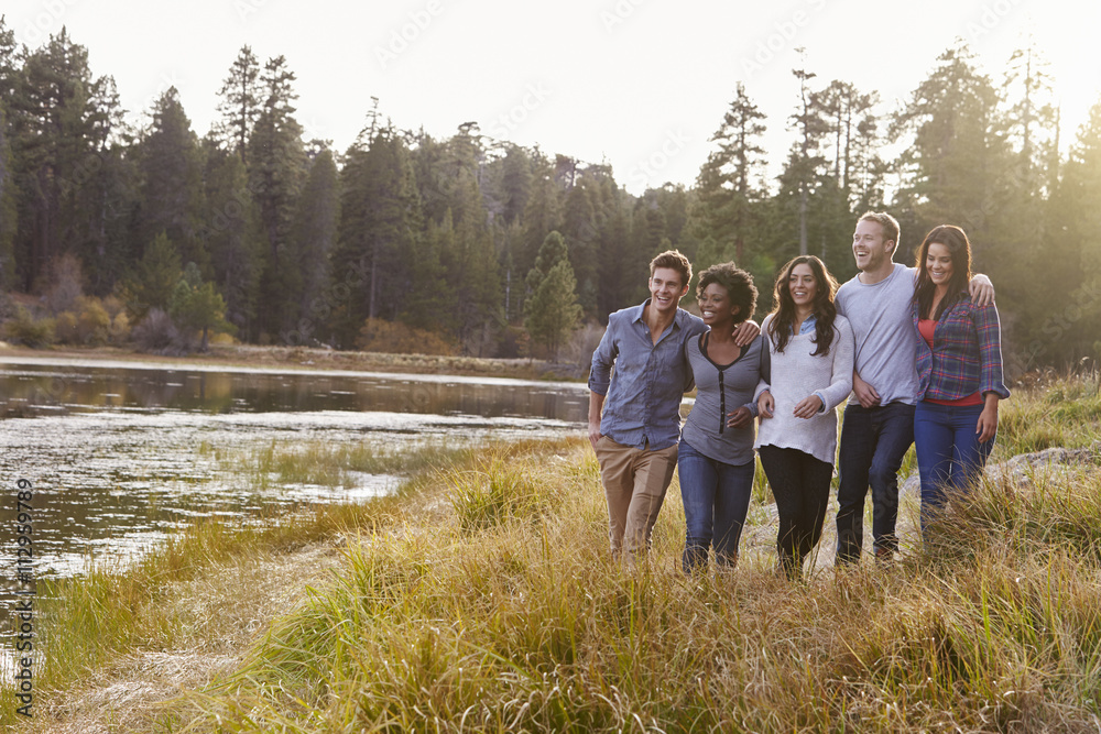 Group of five happy friends walking near a rural lake Group of five happy friends walking near a rural lake