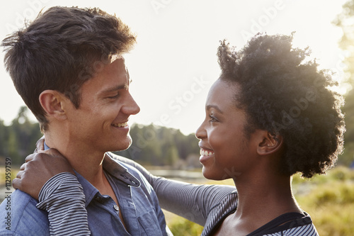 Happy mixed race couple embracing in the countryside