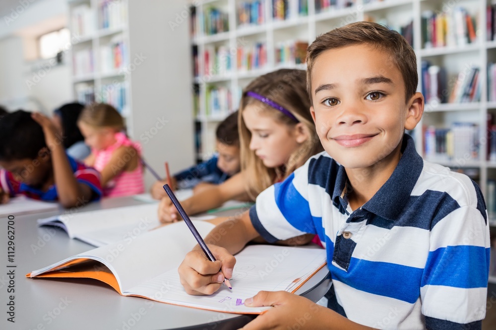 Little boy posing for the camera while he is coloring Little boy posing for the camera while he is coloring