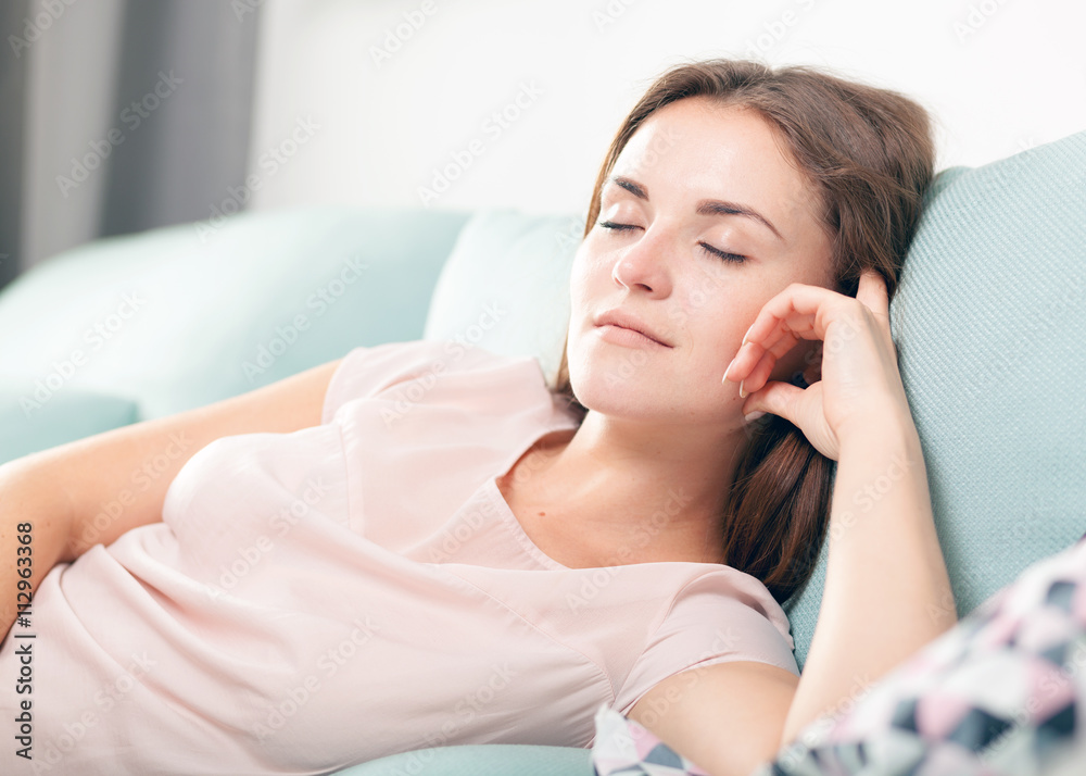 Happy young woman lying on couch and relaxing at home. Casual style indoor shoot Happy young woman lying on couch and relaxing at home. Casual style indoor shoot