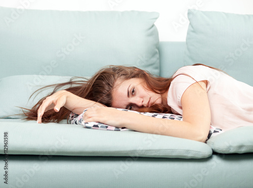 Exhausted young woman lying on couch at home. Casual style indoor shoot