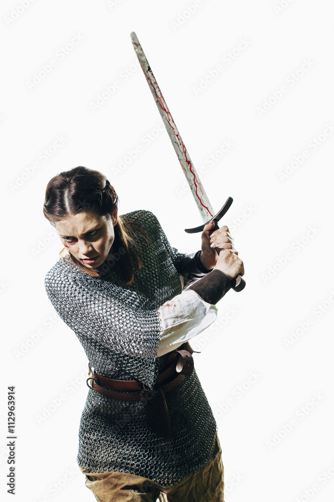 Angry woman wearing chain mail holding sword against white background Angry woman wearing chain mail holding sword against white background