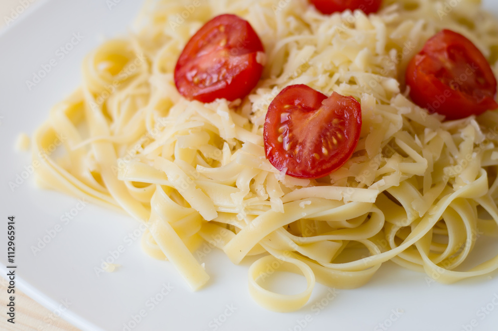 Italian pasta with cheese and cherry tomatoes on a white plate Italian pasta with cheese and cherry tomatoes on a white plate