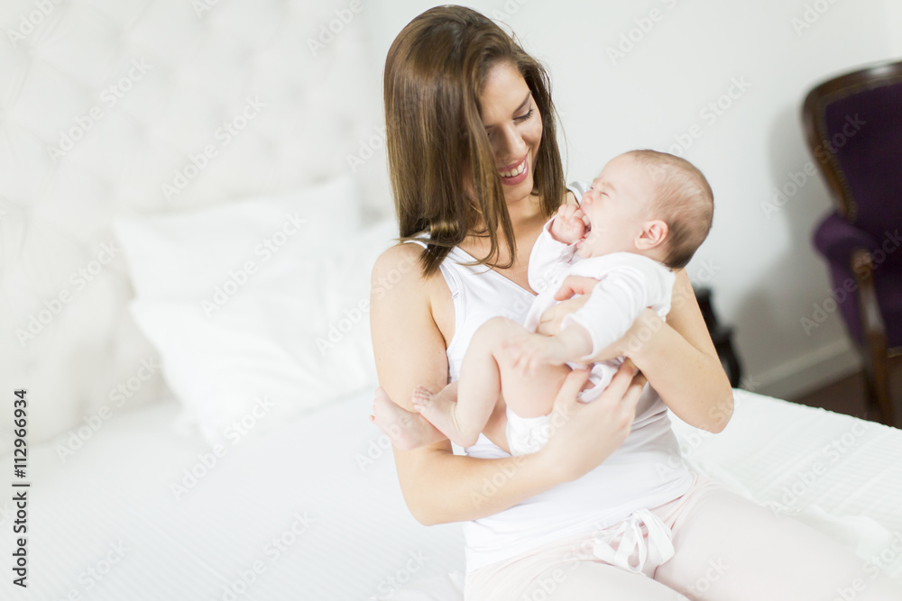 Happy mother with baby on bed Happy mother with baby on bed