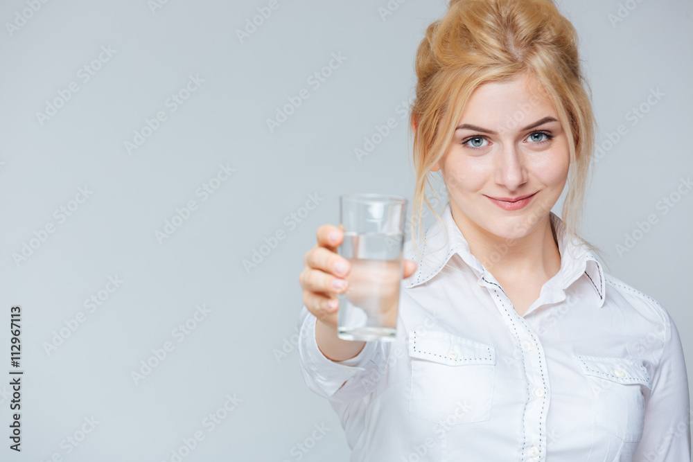 Smiling cute young businesswoman giving you a glass of water Smiling cute young businesswoman giving you a glass of water