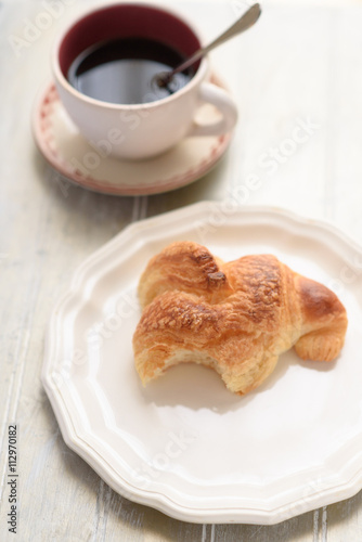 Bited croissant and coffee cup