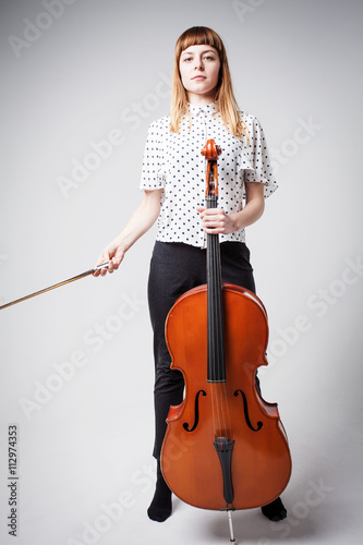 Foto Young cellist standing and playing the cello