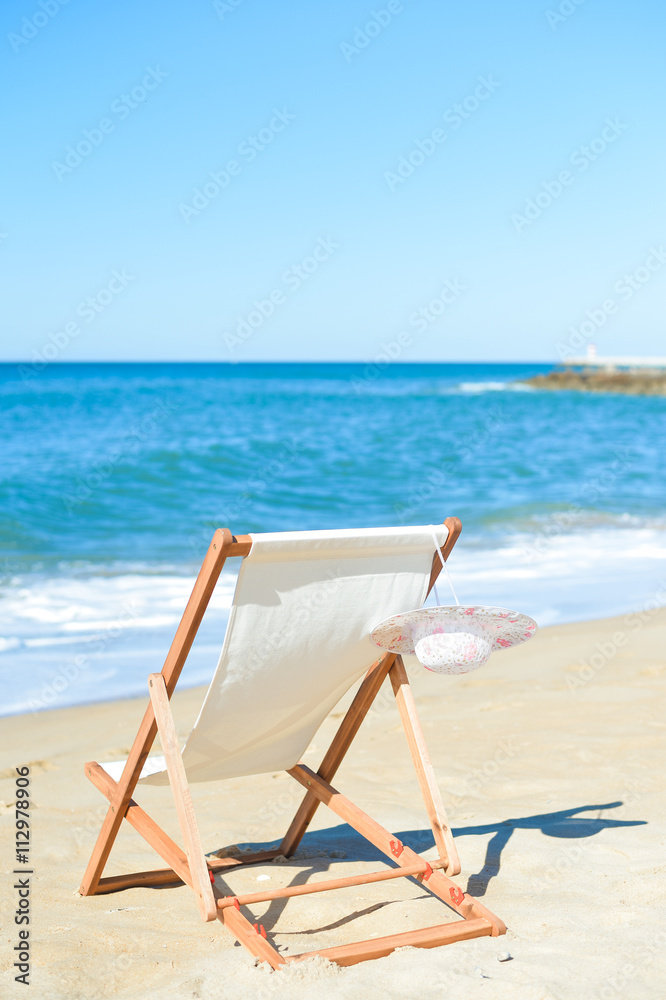 Deckchair and female hat on stunning tropical beach vacation background Deckchair and female hat on stunning tropical beach vacation background