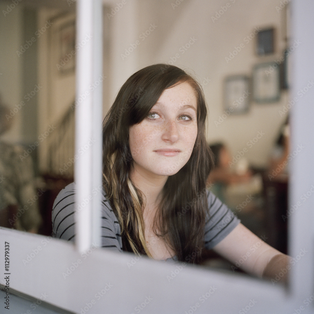 A young woman looking through a window in contemplation A young woman looking through a window in contemplation
