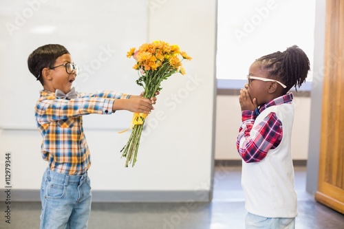 Schoolboy giving a bunch of flowers to a girl photo