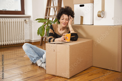 A cheerful woman taking a coffee break while moving house photo