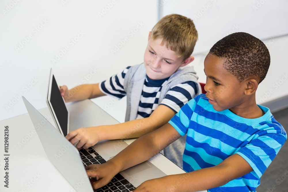 School kids using a laptop and digital tablet in classroom School kids using a laptop and digital tablet in classroom