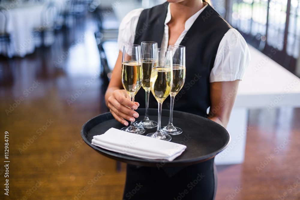 Mid section of waitress holding tray with champagne