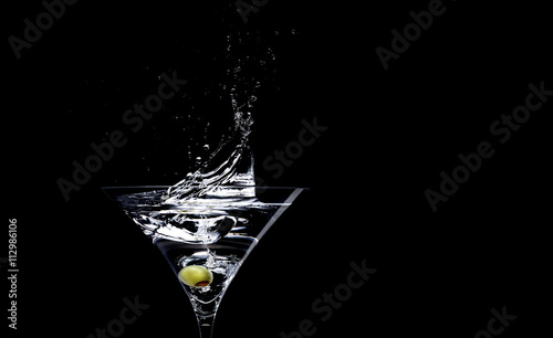 Martini with olive against black background