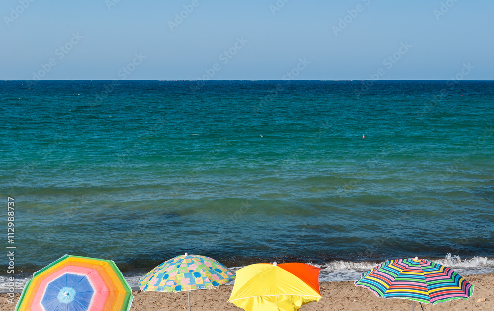 Four beach umbrellas in a beach of Sicily during the summer Four beach umbrellas in a beach of Sicily during the summer