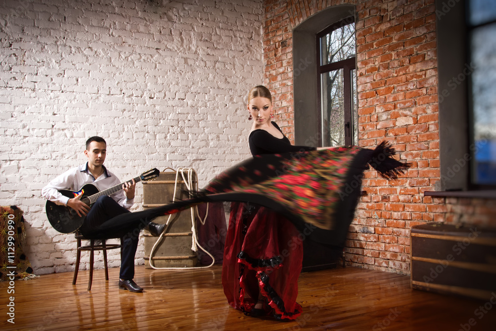 Obraz premium Young woman dancing flamenco and a man playing the guitar