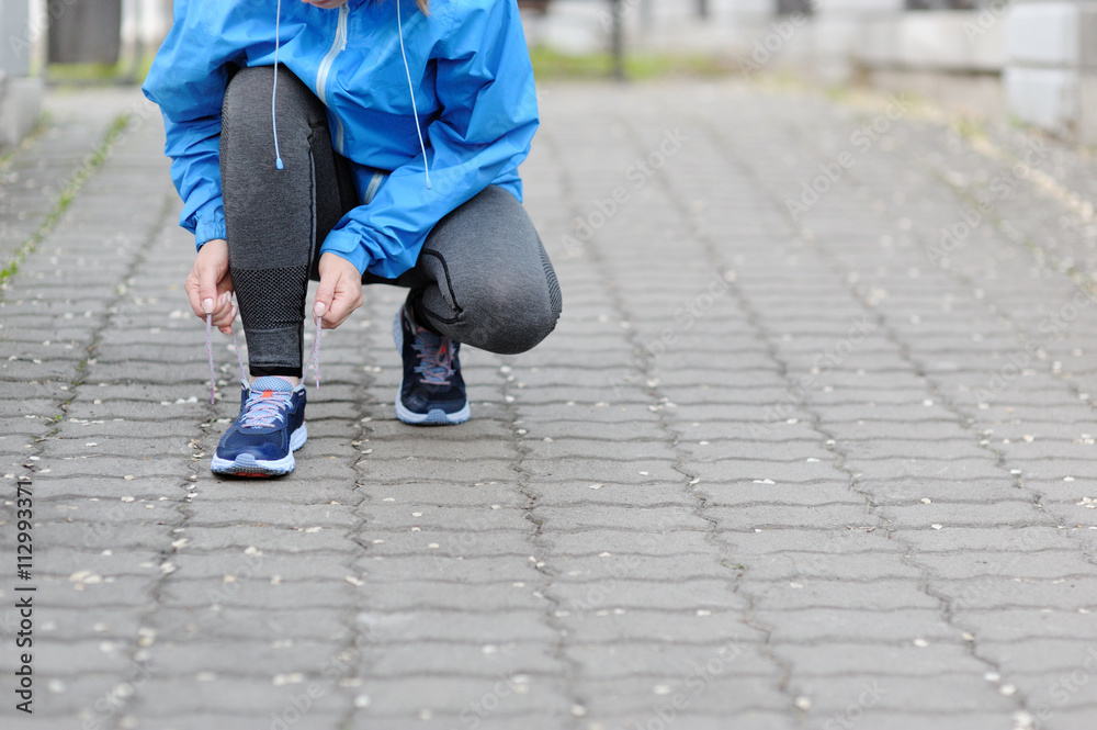 Woman runner tying laces before training. Marathon.