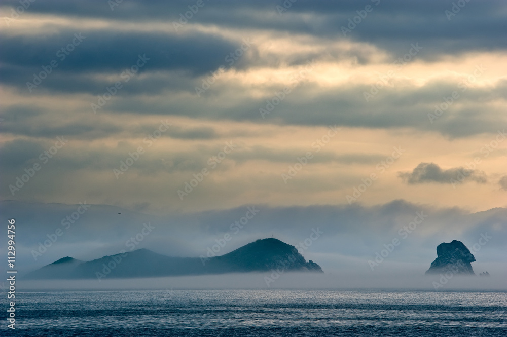 Mist covers the seaside at dawn.