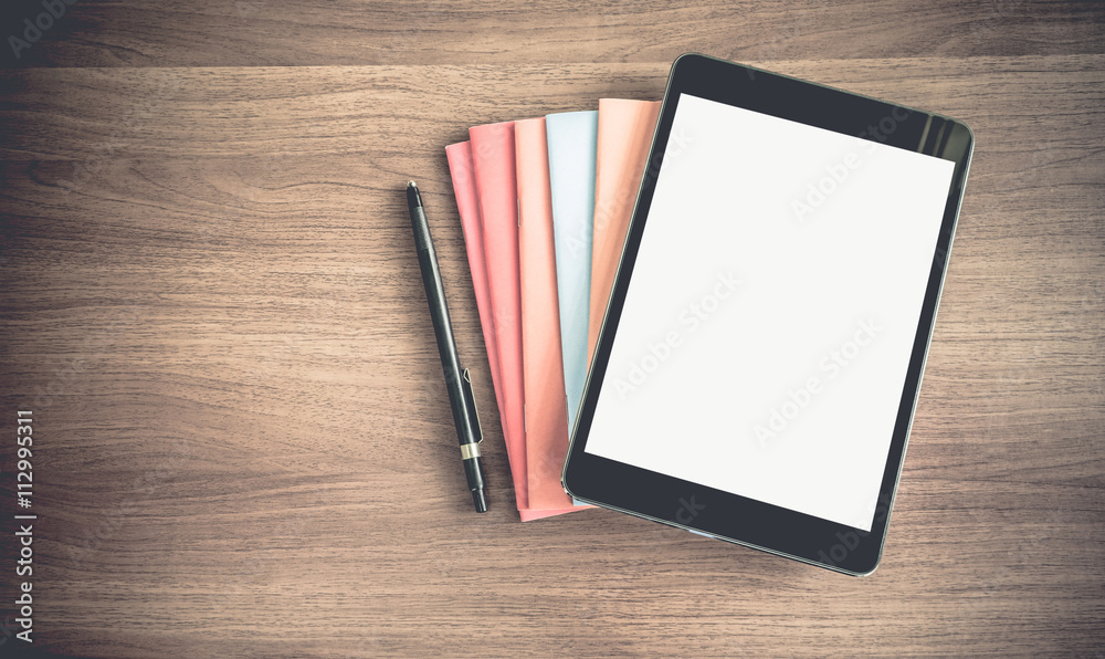 top view of blank screen tablet on stack of book on dark brown w top view of blank screen tablet on stack of book on dark brown w